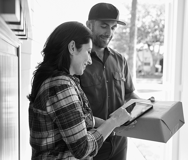 Woman Signing For Package From Courier At Home
